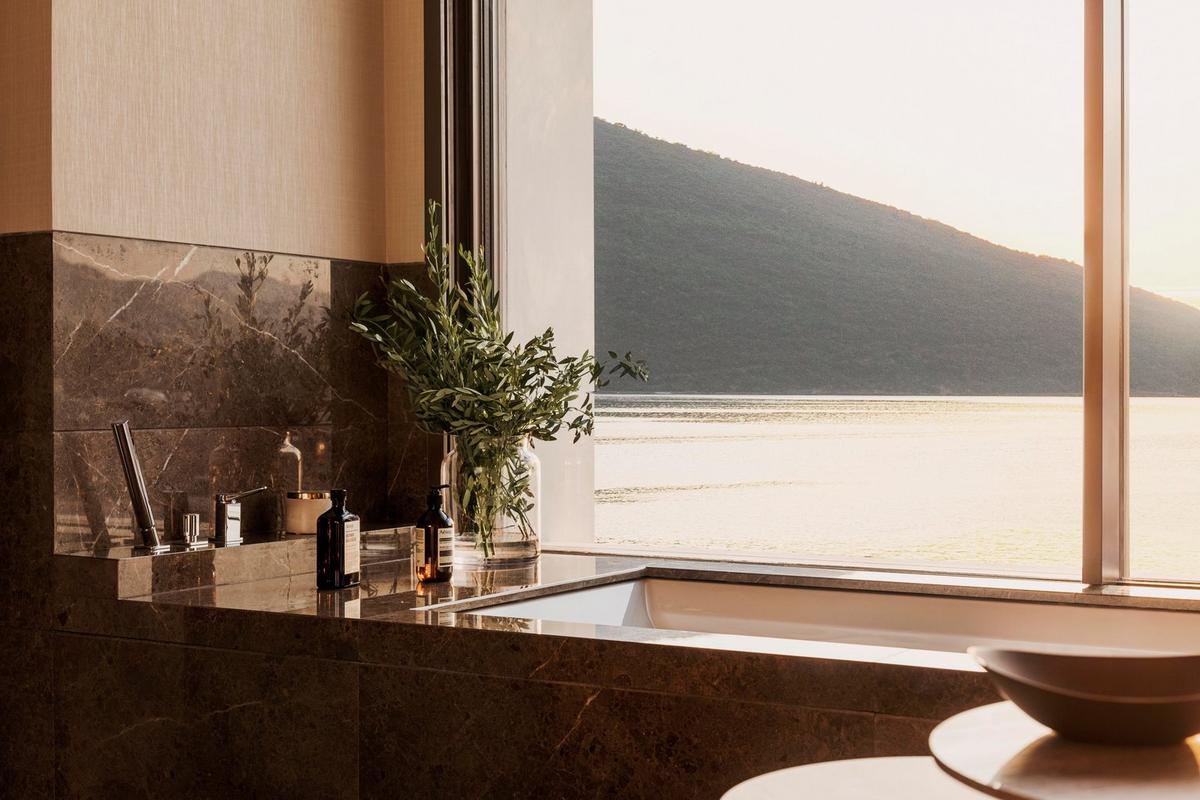 One&Only Portonovi - A marble bathroom with a soaking tub overlooking the bay