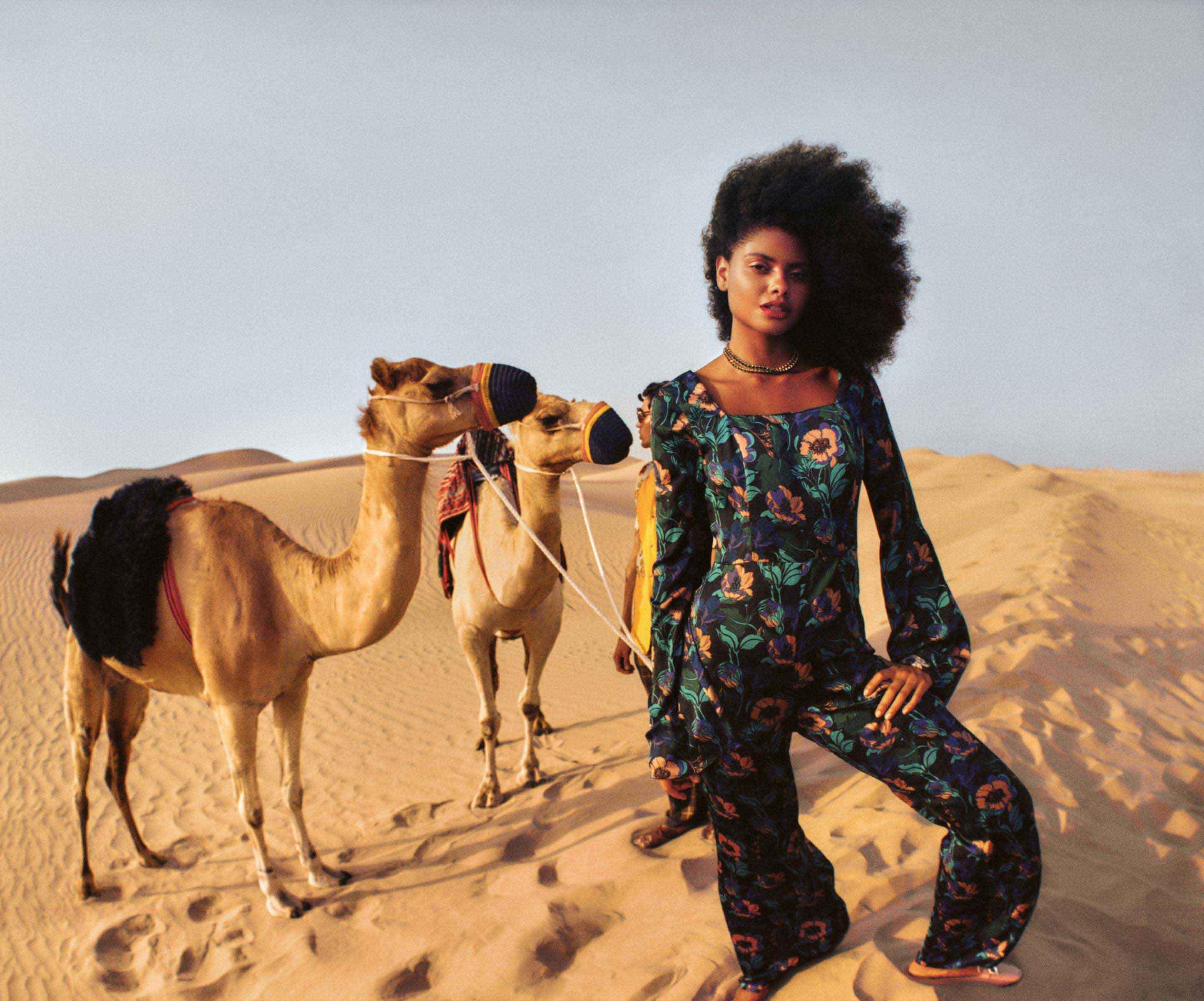 A woman with camels in Dubai's desert landscape